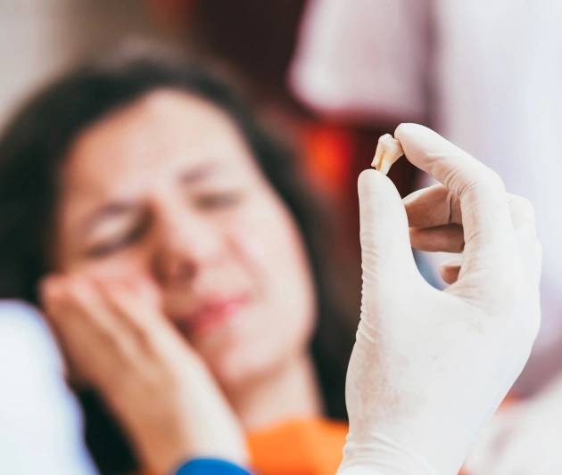 Dentist holding woman's wisdom teeth after the wisdom teeth removal procedure at Warwick Dental