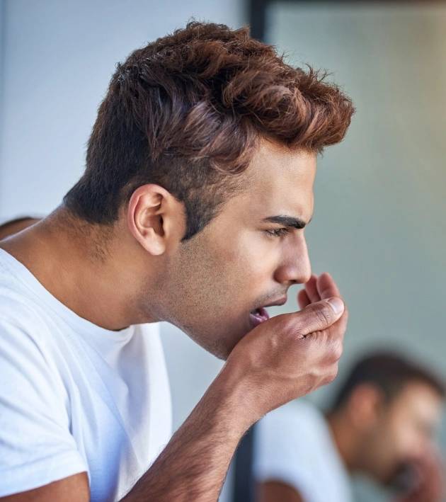 A man checking his breath urgently needs halitosis treatment at Warwick Dental.