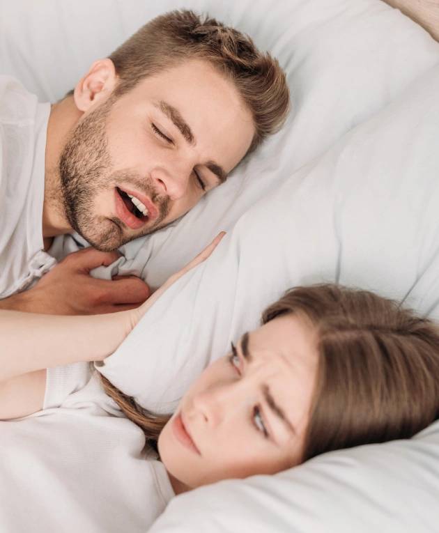 A woman irritated by her partner snoring while lying in bed requires a sleep apnea treatment at Warwick Dental.